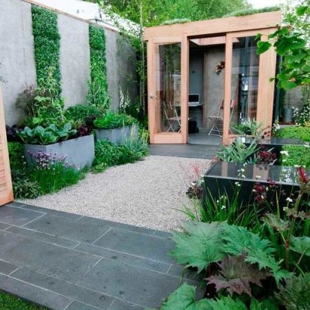 Terraza con parterres y suelos de piedra, grandes jardineras de hormigón.