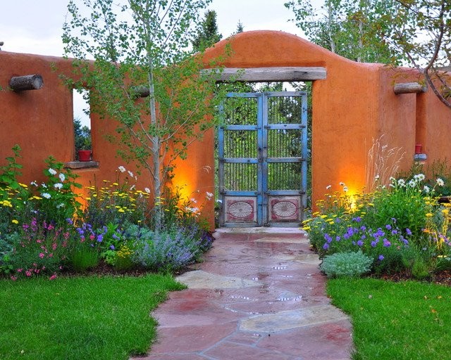 Jardín verde con paredes naranjas y puerta con barrotes